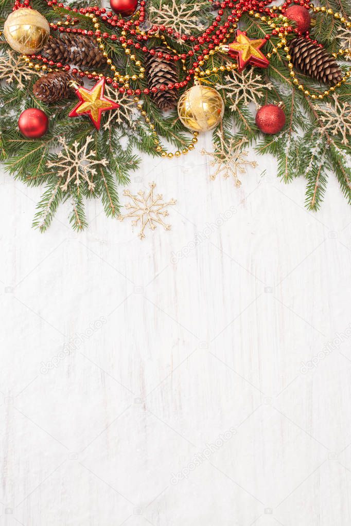 Spruce branches with Christmas ornaments on white wooden background