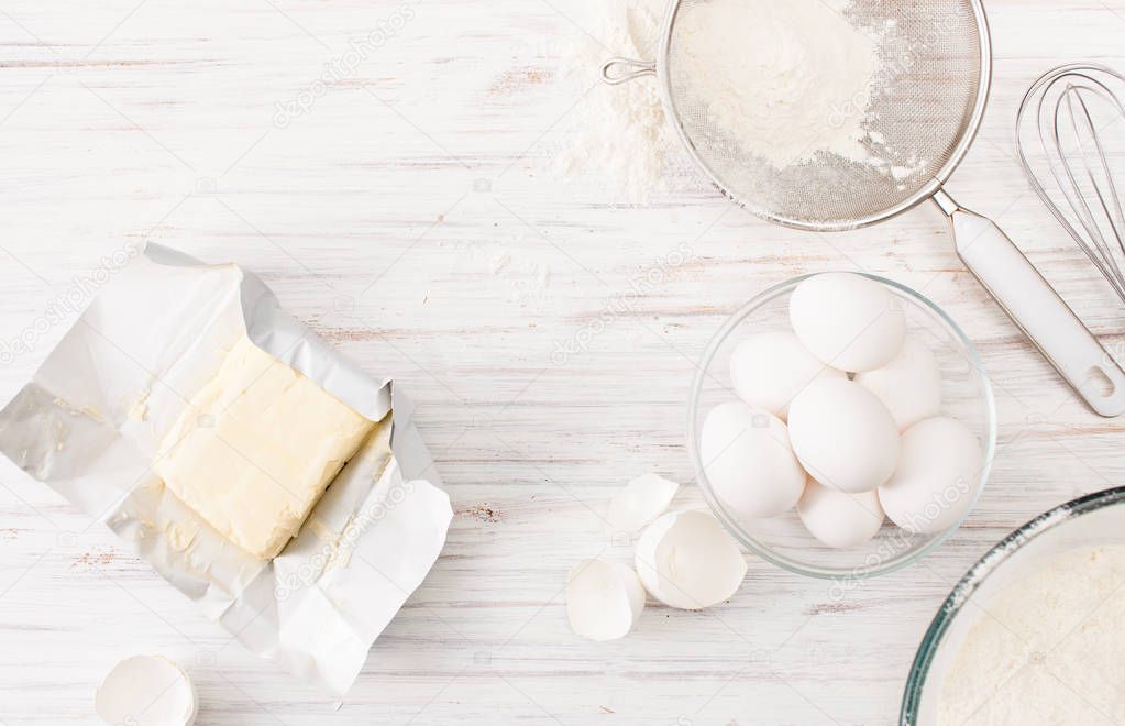 Eggs, flour, butter on a white table. Place for text.