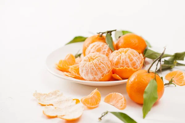 Mandarini pelati e buccia con foglie su sfondo bianco — Foto Stock