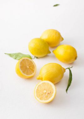 Limon ile bir sürü yaprakları ve limon beyaz bir beton zemin üzerine dilimlenmiş.