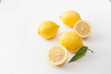 Limon ile bir sürü yaprakları ve limon beyaz bir beton zemin üzerine dilimlenmiş.