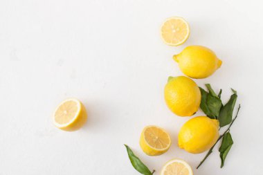 Limon ile bir sürü yaprakları ve limon beyaz bir beton zemin üzerine dilimlenmiş.