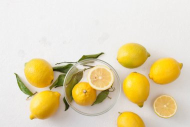 Limon ile bir sürü yaprakları ve limon beyaz bir beton zemin üzerine dilimlenmiş.