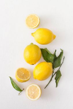 Limon ile bir sürü yaprakları ve limon beyaz bir beton zemin üzerine dilimlenmiş.