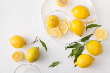 Limon ile bir sürü yaprakları ve limon beyaz bir beton zemin üzerine dilimlenmiş.