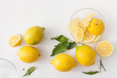 Limon ile bir sürü yaprakları ve limon beyaz bir beton zemin üzerine dilimlenmiş.