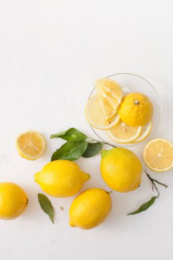 Limon ile bir sürü yaprakları ve limon beyaz bir beton zemin üzerine dilimlenmiş.