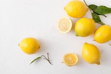 Limon ile bir sürü yaprakları ve limon beyaz bir beton zemin üzerine dilimlenmiş.