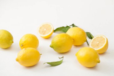 Limon ile bir sürü yaprakları ve limon beyaz bir beton zemin üzerine dilimlenmiş.