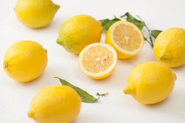 Limon ile bir sürü yaprakları ve limon beyaz bir beton zemin üzerine dilimlenmiş.