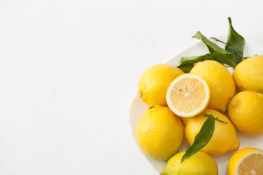 Limon ile bir sürü yaprakları ve limon beyaz bir beton zemin üzerine dilimlenmiş.