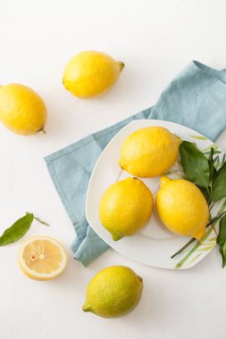 Limon ile bir sürü yaprakları ve limon beyaz bir beton zemin üzerine dilimlenmiş.