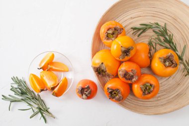 Bir sürü beyaz bir tabloda bir kasede olgun hurma