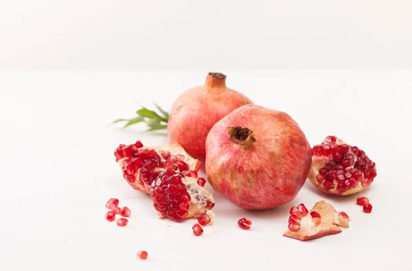 The broken pomegranate fruit with leaves on white — Stock Photo, Image