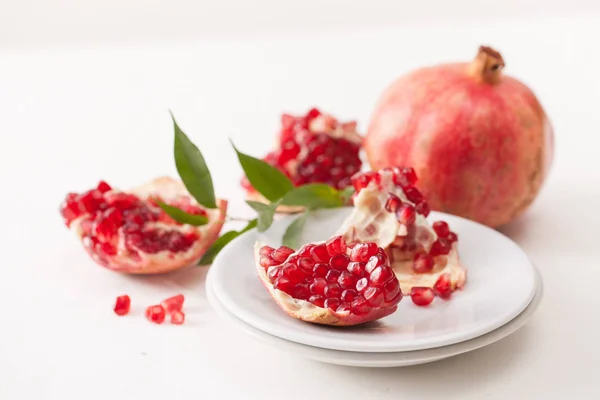 Le fruit de grenade cassé avec des feuilles sur blanc — Photo