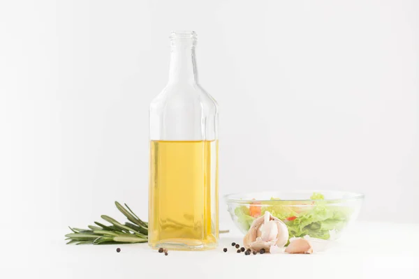 Oil in a bottle with spices and vegetable salad on white — Stock Photo, Image