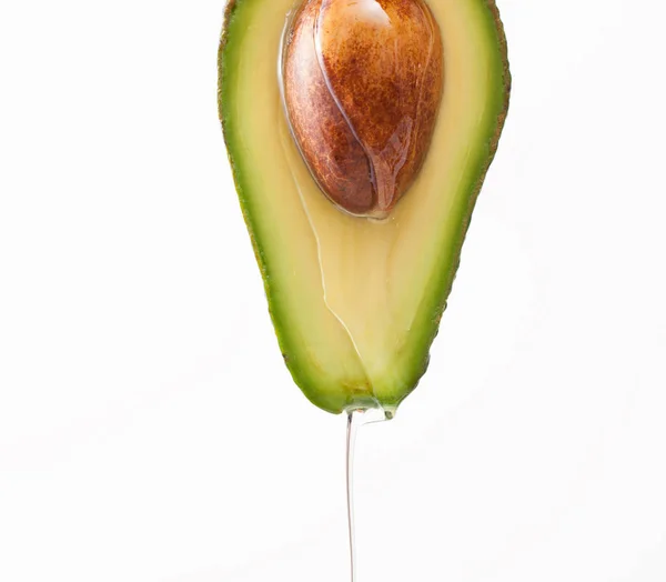 Tropfendes Öl auf einer geschnittenen Avocado auf weißem Hintergrund — Stockfoto