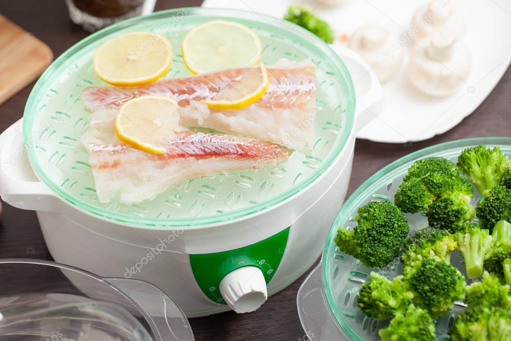 The steamer with the fish and broccoli in the kitchen