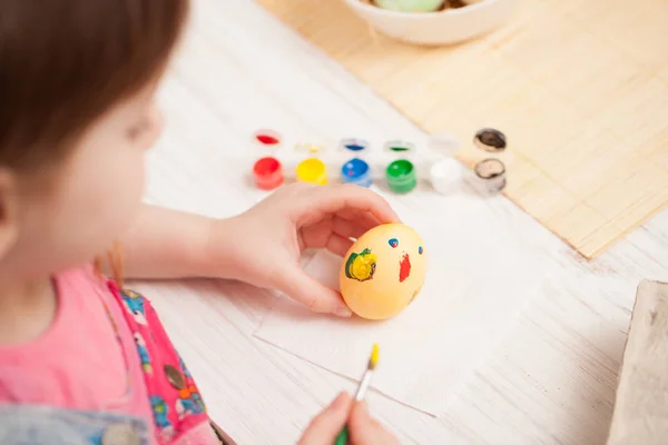 La chica pinta el huevo en la mesa en casa —  Fotos de Stock
