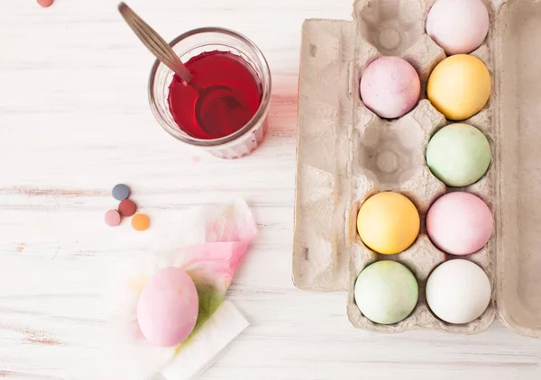 Кольорові яйця в коробці і розфарбовані яйця зі склянкою розведеної фарби — стокове фото