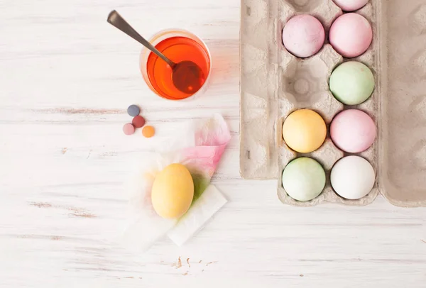 Huevos coloreados en una caja y huevo pintado con un vaso de pintura diluida — Foto de Stock