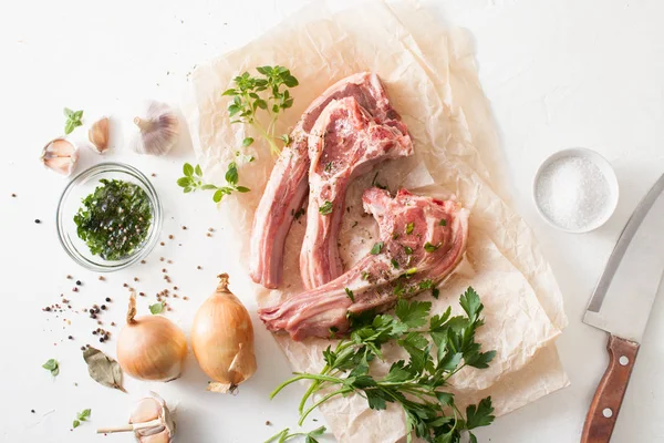 Carne fresca con especias sobre papel de hornear sobre mesa blanca — Foto de Stock