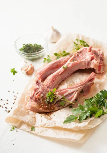 Carne fresca con especias sobre papel de hornear sobre mesa blanca —  Fotos de Stock