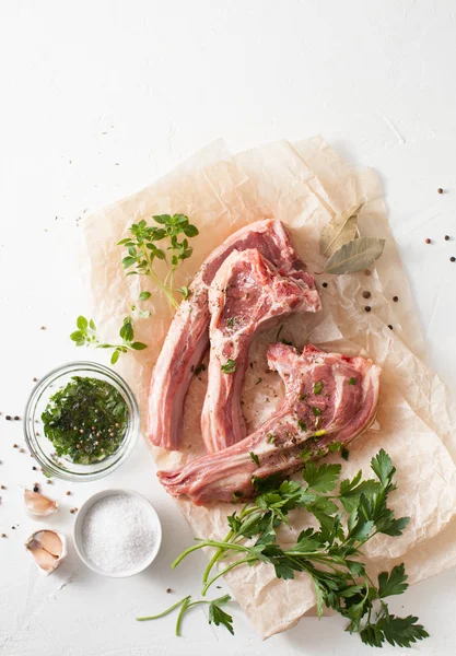 Carne fresca con especias sobre papel de hornear sobre mesa blanca —  Fotos de Stock
