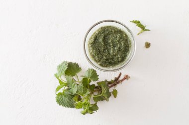 Beyaz üzerine taze ısırgan bir delikanlı ve bir fincan kıyılmış ısırgan