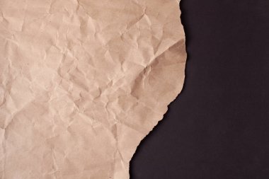 Siyah arka planda yırtık kenarlı buruşuk geri dönüşümlü kağıt