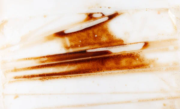 Struttura di fondo di un film trasparente in polietilene con striature liquide marroni — Foto Stock