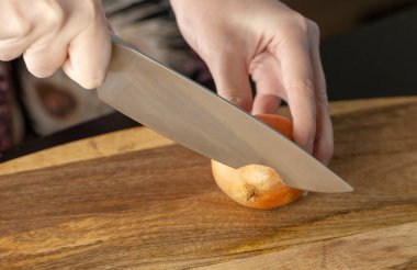 Aşçı odun kesme tahtasıyla soğan doğruyor. Yakın çekim..