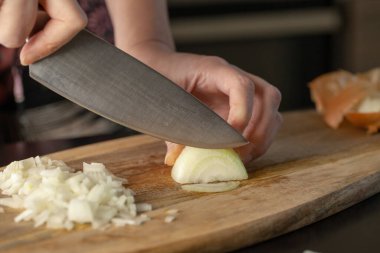 Aşçı odun kesme tahtasıyla soğan doğruyor. Yakın çekim..