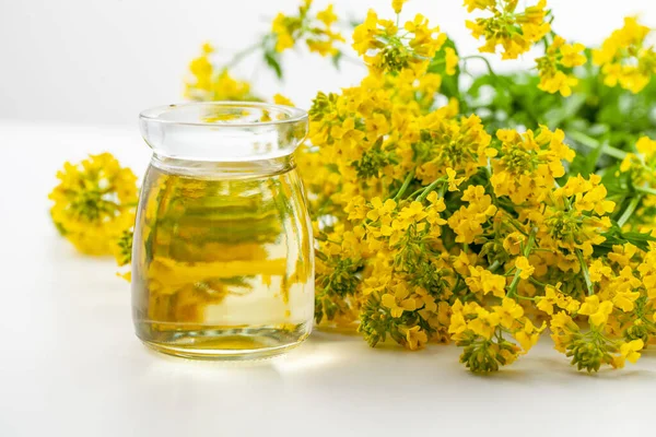 代替医療や健康的な栄養の治療のために白の背景にスプレカの花と菜種油の瓶が使用されています — ストック写真