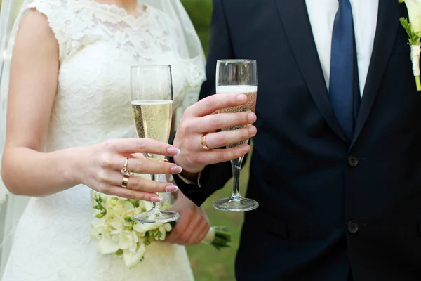 Bruidspaar houden bril met champagne in hun armen — Stockfoto