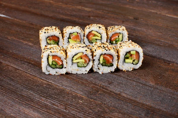 Färsk sushi-roller på en träplatta med händerna på kocken i bakgrunden — Stockfoto