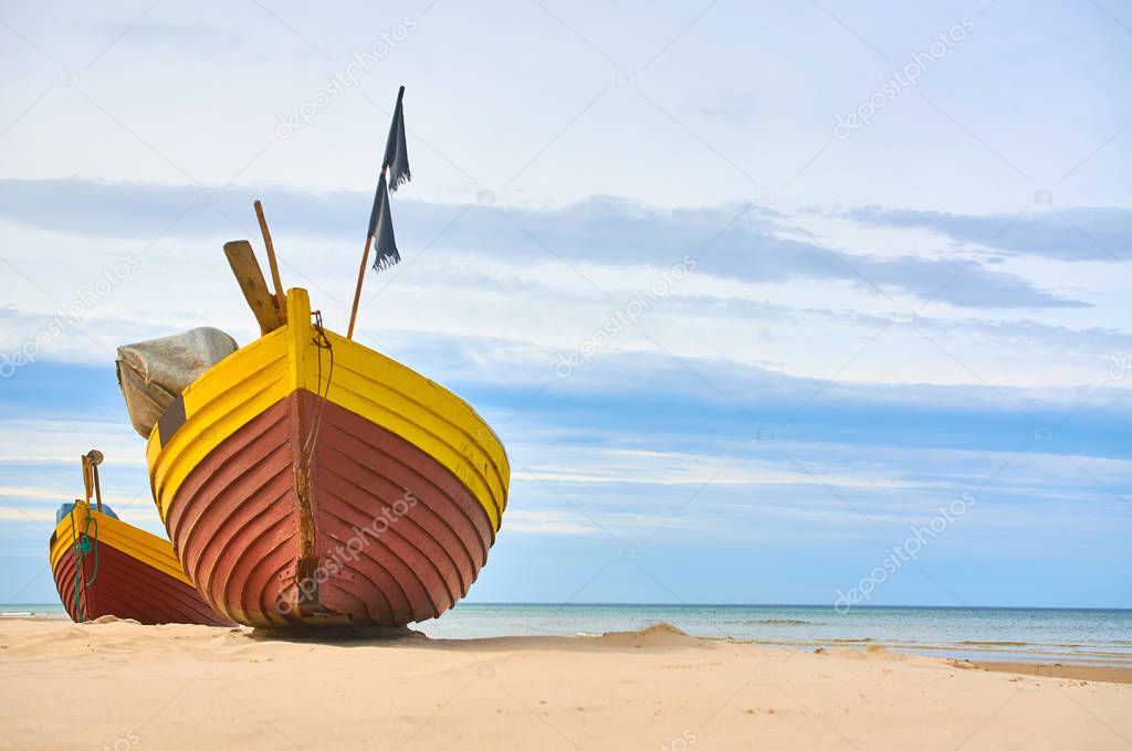 Fishing boat at baltic sea sandy beach with dramatic sky during summertime in Poland