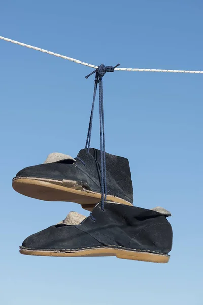 Blue suede old boots hanging from a rope — Stock Photo, Image