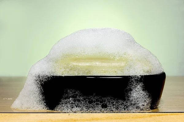Green soap with foam on a black soap — Stock Photo, Image