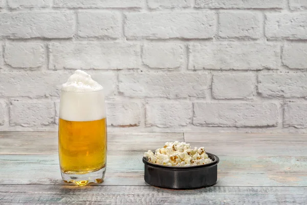 Vaso de cerveza con espuma y tazón con palomitas de maíz — Foto de Stock