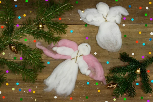 Kartki świąteczne: dwa białe wełniane anioły latające, kolorowy konfetti i wiecznie zielone gałęzie na deski. — Zdjęcie stockowe