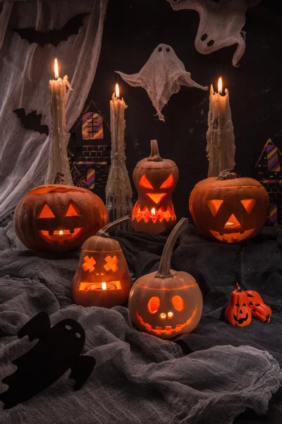 The pumpkin heads of Halloween with candles, a web, bats and ghosts against a dark background