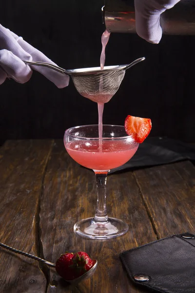 Jordgubben cocktail med en jordgubbe bit filtreras genom en sil — Stockfoto
