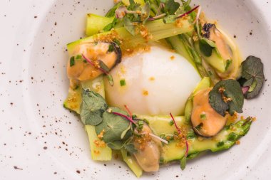 Sos ve midye yeşillikleri ile yuvarlak tabakta ile kuşkonmaz