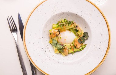 Sos, midye, kaz yumurtası bir beyaz kuşkonmaz plaka, cihazlar ile beyaz bir bez tarafından sunulan tablo üzerinde yuvarlak