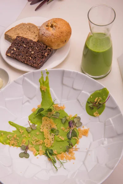 Diseño de la mesa. Sopa de guisantes verdes con el queso crujiente, una canasta de pan casero y hierbas —  Fotos de Stock