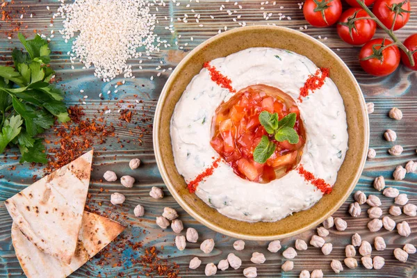 Hummus, el garbanzo limpiado con pasta de sésamo, aceite de oliva, pomidoro y perejil —  Fotos de Stock