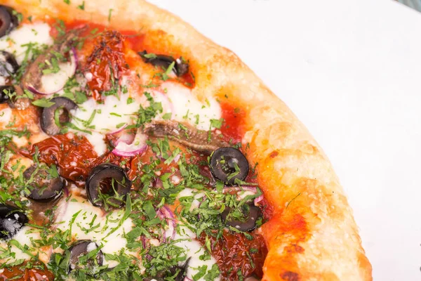 Kurutulmuş domates, hamsi, kırmızı soğan, bir pizza parça peynir bir mozzarella, zeytin ve maydanoz