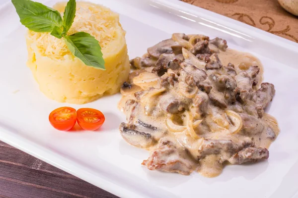 Borjúhús, hagyma és a gombára gyengéd tejszínes mártással, párolt tálalva sajtos burgonyapürével — Stock Fotó