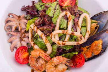 Karides salata, midye, mürekkep beyaz şarap ile servis edilir ve zeytin yağı